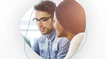 Two people having a conversation, one wearing glasses.