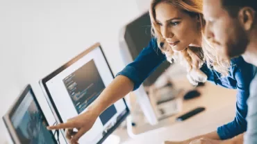 Two people collaborating at a computer in an office setting.