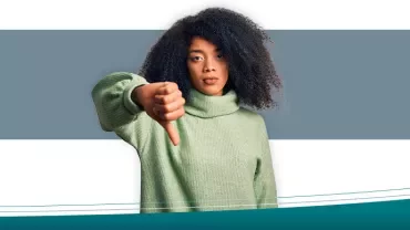 Woman in green sweater giving thumbs down gesture.