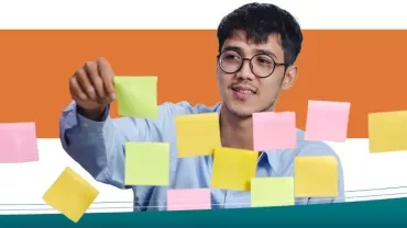 A man placing sticky notes on a transparent board.