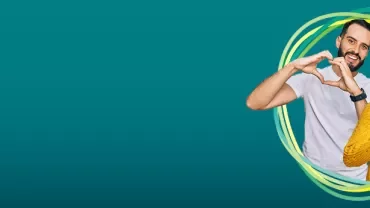 Two people making heart shapes with hands on a teal background.
