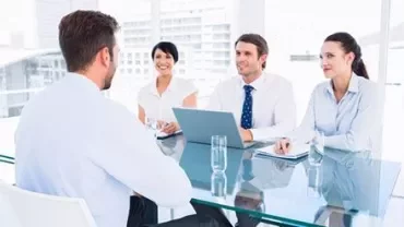Zakelijke bijeenkomst met vier personen aan een glazen tafel.