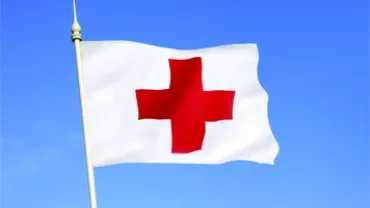 Red Cross flag waving against a clear blue sky.