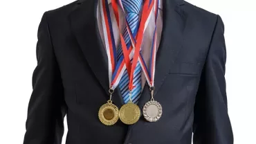 Person in suit wearing three medals with ribbons.