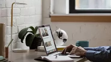 Persoon typt op laptop in een gezellige thuiskantoor.