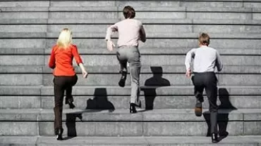 Three people climbing outdoor stairs in business attire.