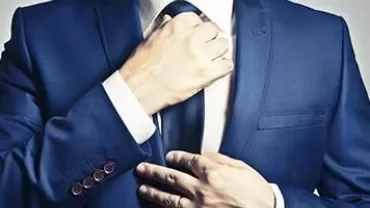 Man adjusting his blue suit and tie.