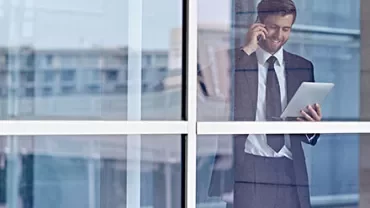 Homme d'affaires au téléphone et tablette près de la fenêtre.