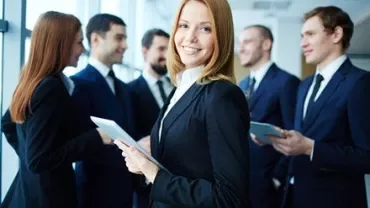 Groupe de professionnels en réunion, femme souriante au premier plan avec une tablette.