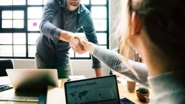 Deux personnes se serrent la main dans un bureau.