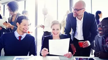 Group of colleagues discussing paperwork at a desk.