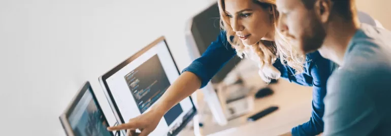 Two people collaborating at a computer in an office setting.