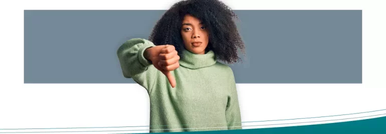 Woman in green sweater giving thumbs down gesture.