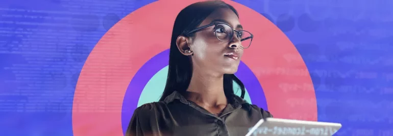 Woman with glasses holding a tablet against a colorful background.