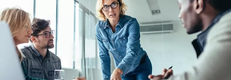 Une femme professionnelle faisant une présentation à ses collègues dans un bureau moderne.