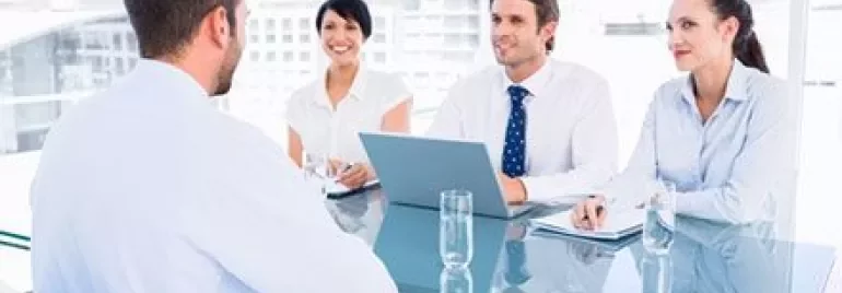 Zakelijke bijeenkomst met vier personen aan een glazen tafel.