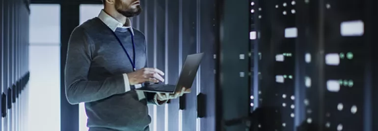 Personne utilisant un ordinateur portable dans une salle de serveurs.