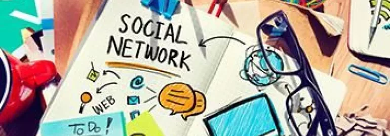 Bureau met bril, notitieblok met 'Social Network' schetsen en kleurrijke kantoorbenodigdheden.