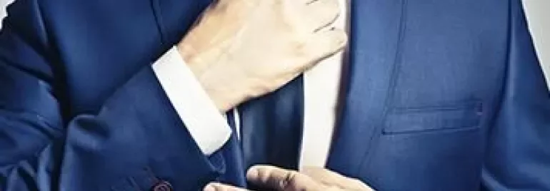 Man adjusting his blue suit and tie.