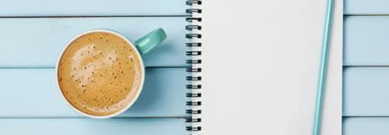 To-do list on a notepad with pencil and coffee on a blue table.