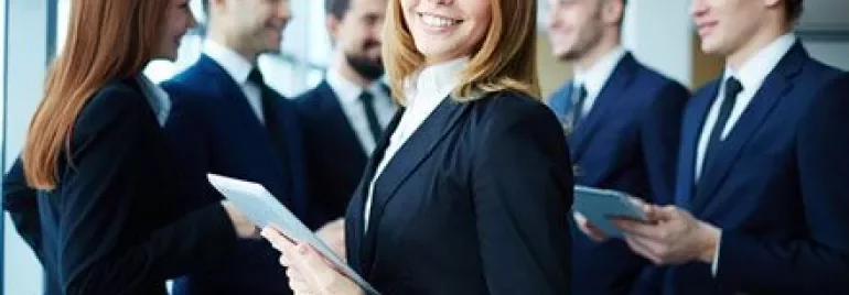 Groep professionals in een vergadering, glimlachende vrouw met tablet op de voorgrond.