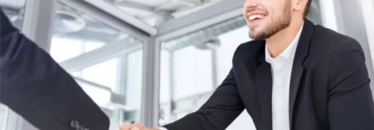 Homme en costume serrant la main dans un bureau moderne.