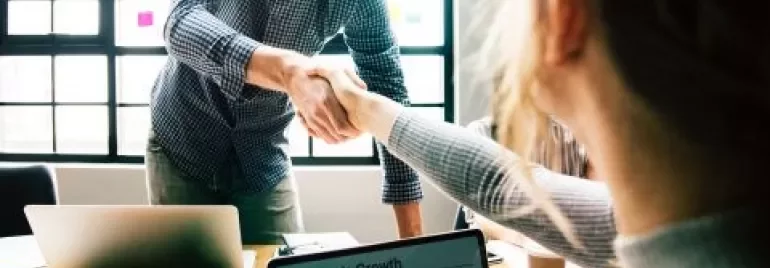 Deux personnes se serrent la main dans un bureau.