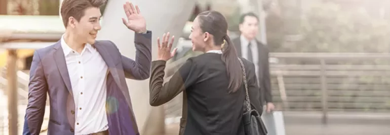 Twee zakenmensen geven elkaar een high five buiten.