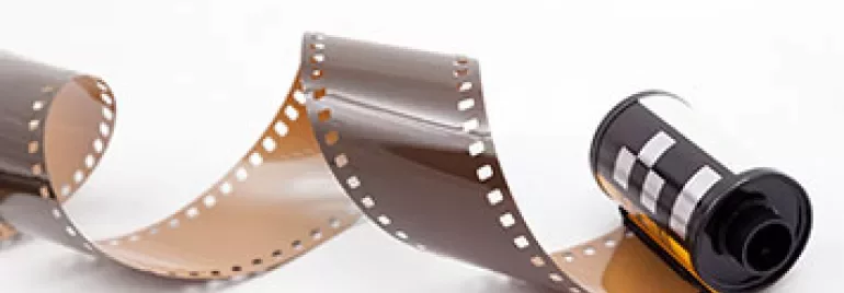 A roll of photographic film partially unspooled on a white background.