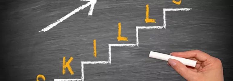 Hand tekent treden met 'skills' op schoolbord