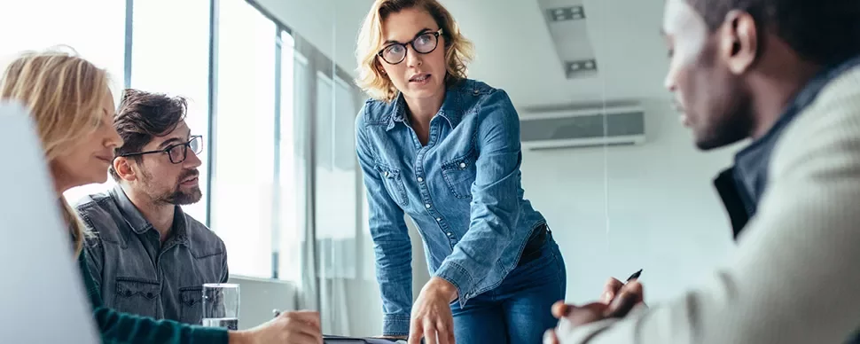 Une femme professionnelle faisant une présentation à ses collègues dans un bureau moderne.