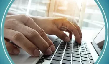 Person typing on a laptop keyboard near a window.