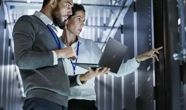 Two professionals checking servers in a data center.