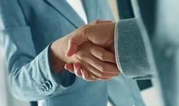 Close-up of a handshake between two people in business attire.