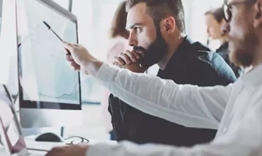 Twee mannen analyseren gegevens op computerschermen.