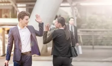 Two business professionals high-fiving outdoors.