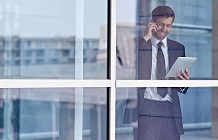 Homme d'affaires au téléphone et tablette près de la fenêtre.